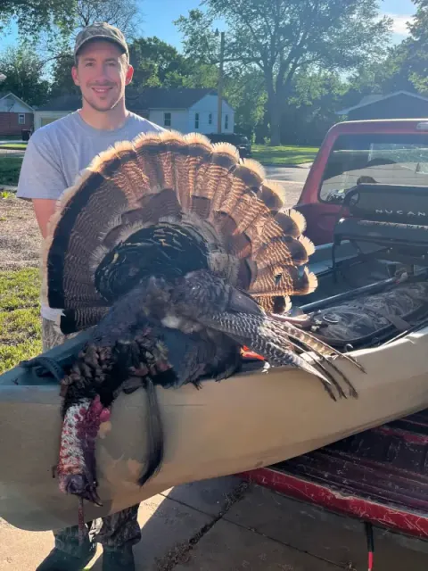 Author standing with a turkey next to NuCanoe Hunting Kayak